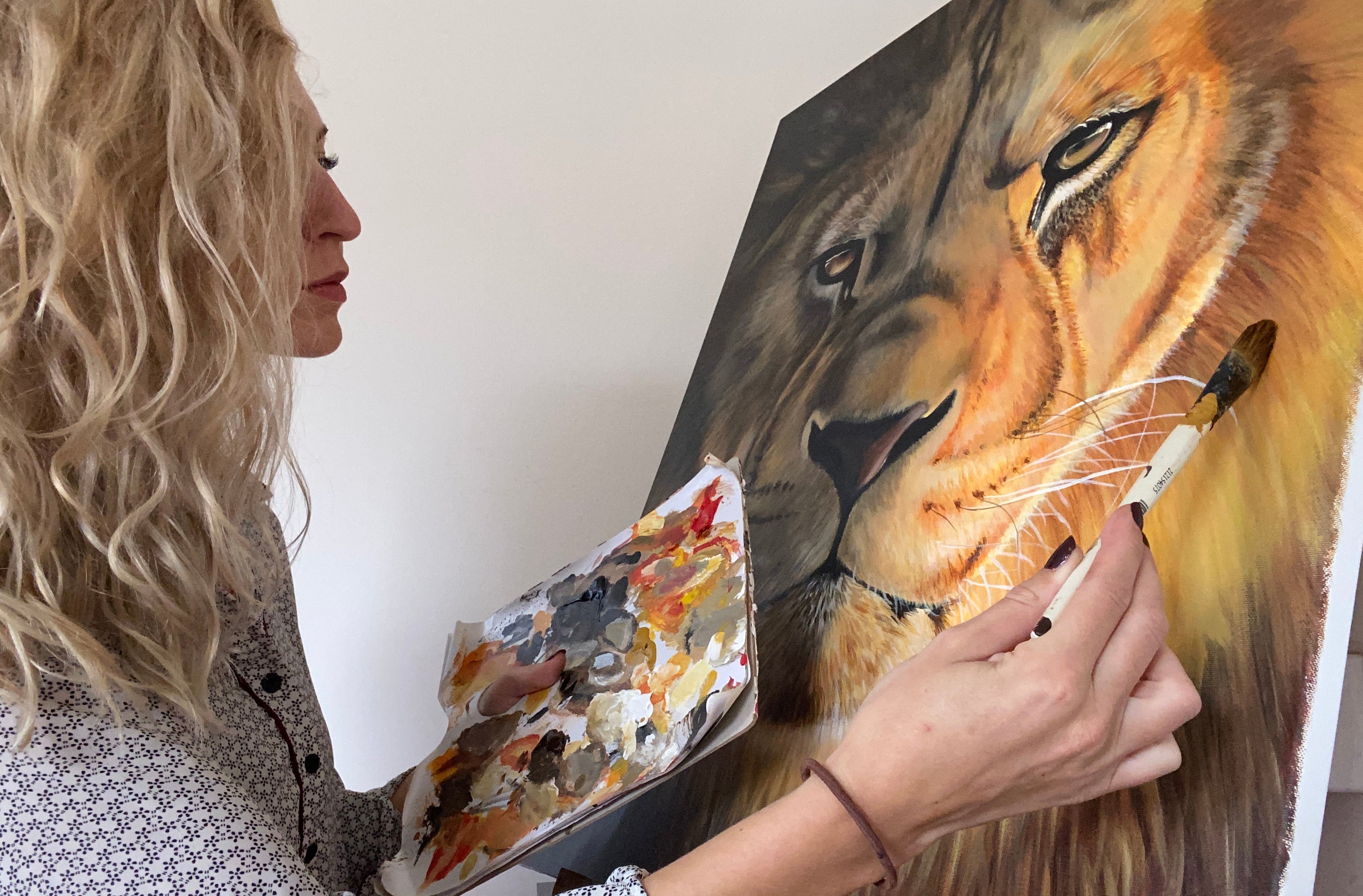Person wearing a patterned shirt and floral shoes, standing next to a painting of a lion.